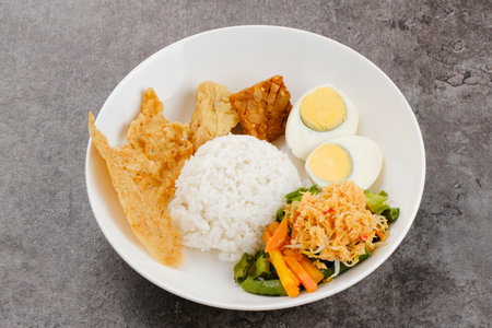 Nasi Gudangan, rice served with various vegetable with grated coconut seasoned and various side dishes. Indonesian foodの写真素材