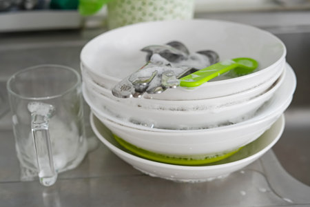 Sink with dirty dishes in kitchen, pile of unwashed plate