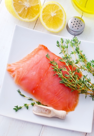 Raw salmon on the white plate with thyme and saltの写真素材