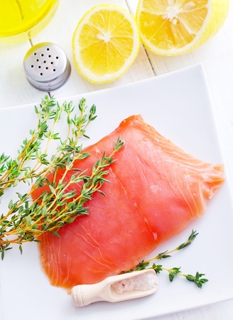 Raw salmon on the white plate with thyme and saltの写真素材