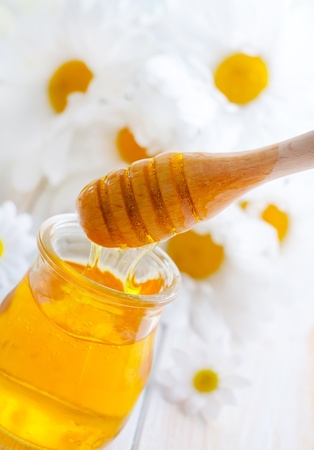 fresh honey in the glass bank and camomilesの写真素材