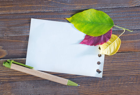 autumn leaves on the wooden background,yellow leaves and notepadの写真素材