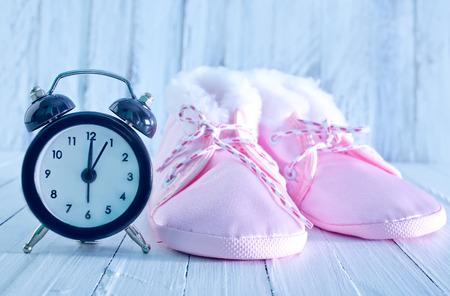 baby shoes and clock on a tableの写真素材