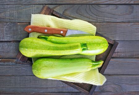 raw zucchini on wooden tray and on a tableの写真素材