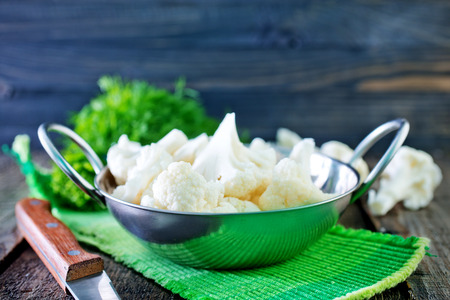 raw cauliflower in the metal bowl and on a tableの写真素材