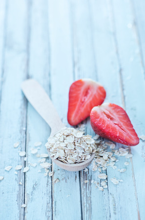 raw oat flakes in spoon and on a tableの写真素材