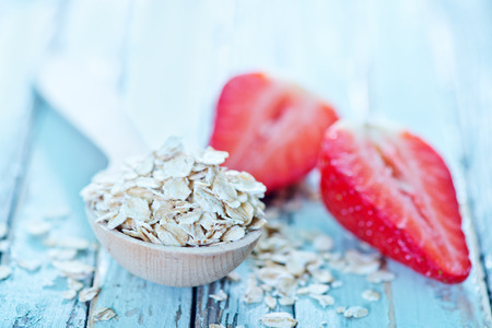 raw oat flakes in spoon and on a tableの写真素材