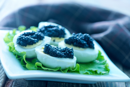 boiled egg with black caviar on plateの写真素材