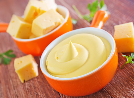 cheese sauce in bowl and on a tableの写真素材