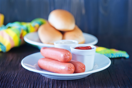 buns and sausages on white plate and on a tableの写真素材