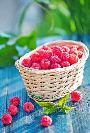fresh raspberry in basket and on a tableの写真素材