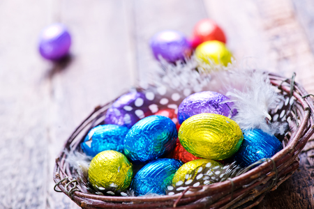 chocolate eggs in color foil and on a tableの写真素材