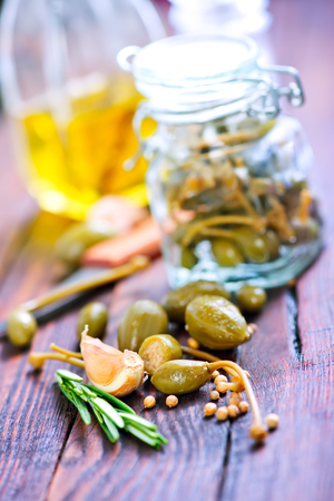 capers in glass bank and on a tableの写真素材