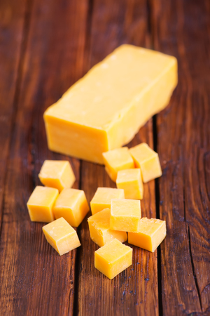 cheddar cheese on board and on a tableの写真素材