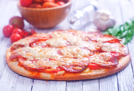 fresh pizza with salami and cheese on a tableの写真素材