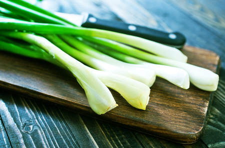 green onion on board and on a tableの写真素材