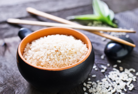 raw rice in bowl and on a tableの写真素材