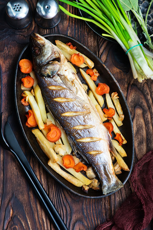 baked fish with vegetable on a tableの写真素材