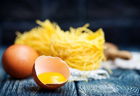 raw egg noodles and yolk on a tableの写真素材