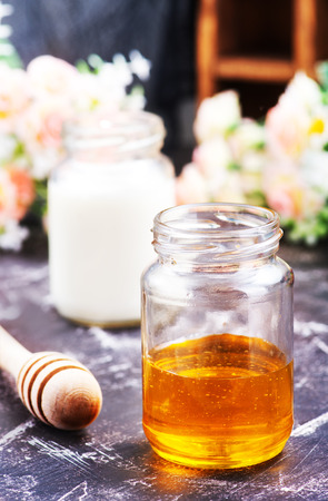 honey in glass bank and milk on a tableの写真素材