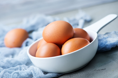 raw eggs in white bowl and on a tableの写真素材