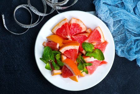 fresh grapefruit on plate and on a tableの写真素材