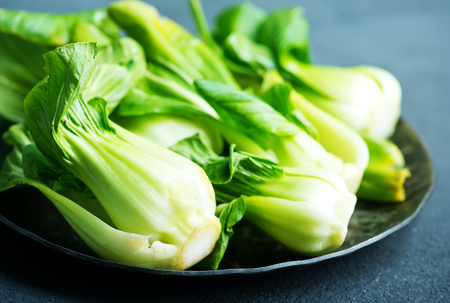 fresh pak choi on plate and on a tableの写真素材