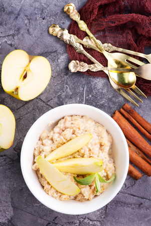 Oatmeal with fresh apples and cinnamon in the bowlの写真素材