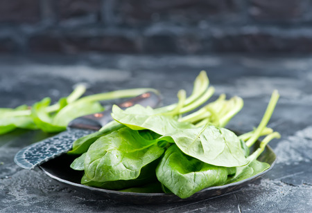 fresh spinach on plate and on a tableの写真素材