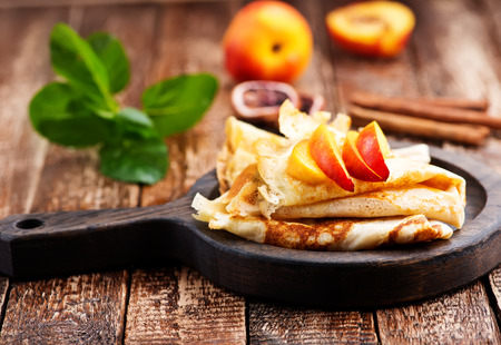 pancake with peach and cinnamon on the wooden boardの写真素材