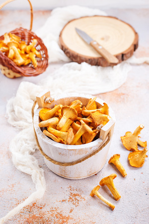 raw mushrooms in white wooden bowl and on a tableの写真素材