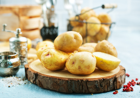 raw potato, potato on wooden board on a tableの写真素材