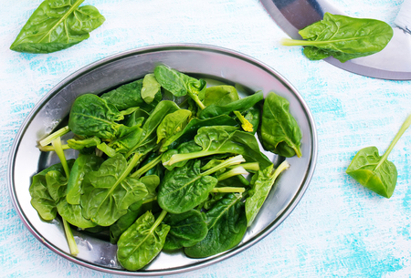 Fresh spinach on metal plate on a tableの写真素材