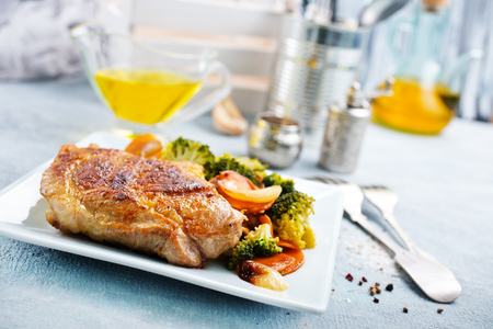 fried meat with vegetables on white plateの写真素材