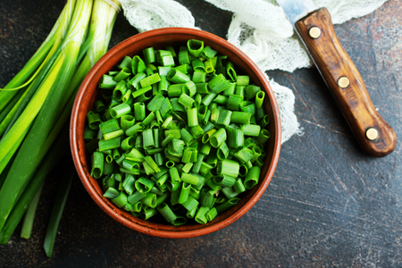 green onion, fresh  onion and knife on kitchen tableの写真素材
