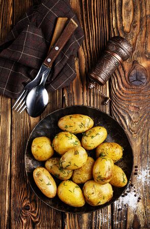 Boiled young potatoes with butter and dill on plate on a dark background.の写真素材