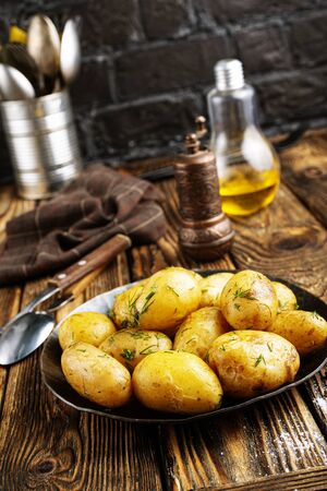 Boiled young potatoes with butter and dill on plate on a dark background.の写真素材