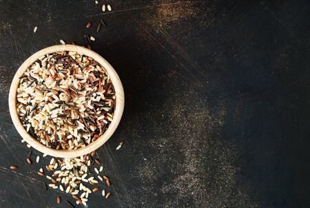 raw rice in wooden bowl on a tableの写真素材