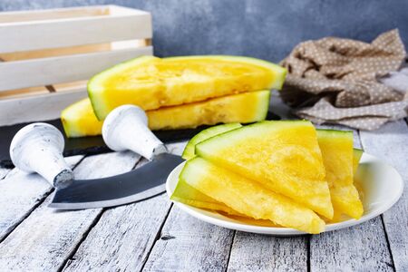 yellow watermelon on plate and on a tableの写真素材