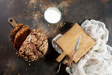 Homemade rustic rye bread with sunflower seeds and a bottle of milk on old tableの写真素材
