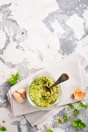 Homemade parsley pesto sauce and ingredients on dark cement background. Close up wiev of basil pesto in glass jar with ingredients.の写真素材