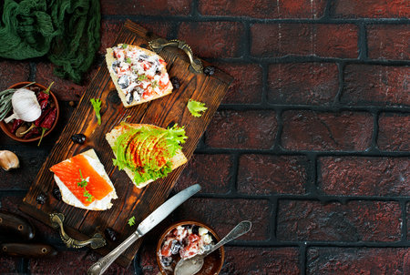 healthy sandwiches with smoked salmon avocado cucumber cream cheese on rye bread on dark backgroundの写真素材