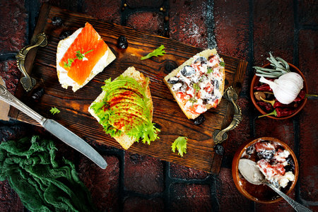 healthy sandwiches with smoked salmon avocado cucumber cream cheese on rye bread on dark background