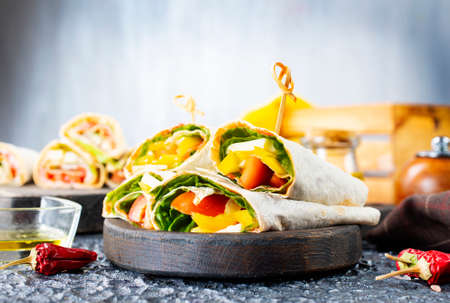 Healthy tortilla wraps viewed from side on wooden cutting board, tortilla with chicken and vegetablesの写真素材