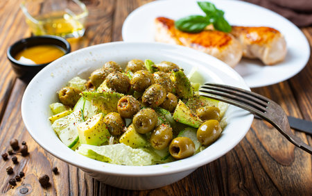 Fresh salad with vegetable: cucumbers, tomatoes, olives, onion, bell pepper, lettuce and herbs and dressed with salt, pepper and olive oil.の写真素材