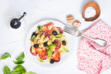 Antipasto salad with pasta, tomato, olives, red onion, bell pepper, salamiの写真素材