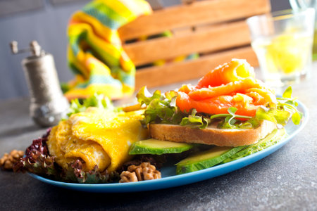 Omelette or omelet, fresh arugula and tomato salad and toasts with butter and salted salmon. breakfast. top viewの写真素材