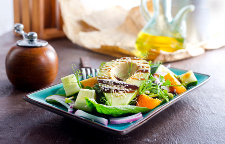 Green vegan salad with cucumber and avocado on a blue table