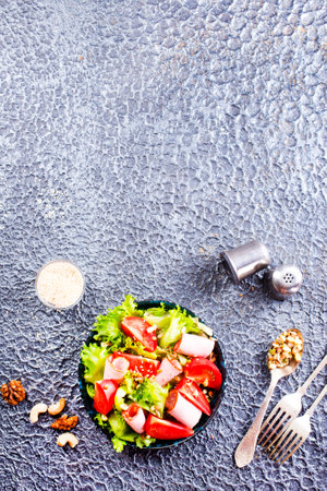 salad with ham and tomato on black plateの写真素材