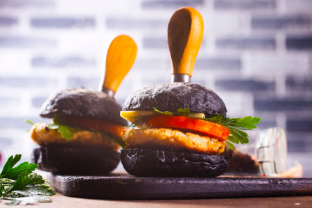 Tasty craft burger with black bun on the boardの写真素材